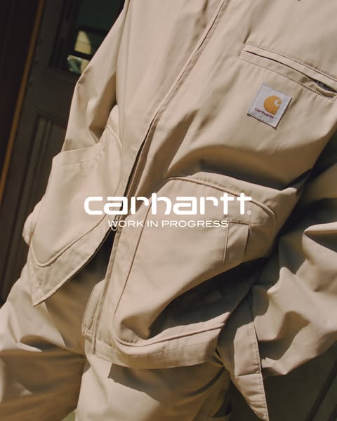 This ad features a close-up of a Carhartt Work In Progress jacket and matching pants. The neutral tan color palette emph