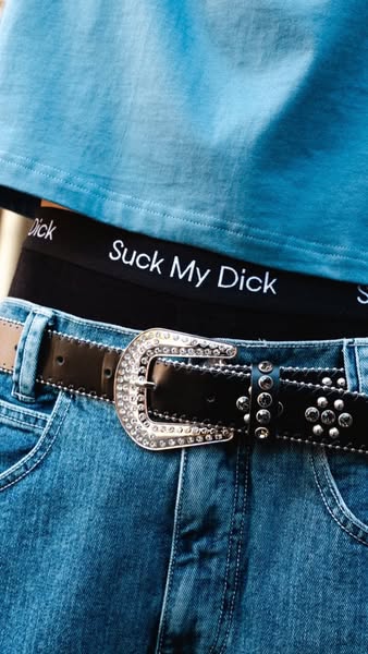 This image ad shows a close-up shot of a person wearing a blue shirt, black underwear with white text on the band, embel