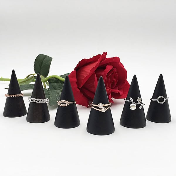 This ad showcases a collection of rings displayed on black cone-shaped stands, with a red rose in the background. The ri