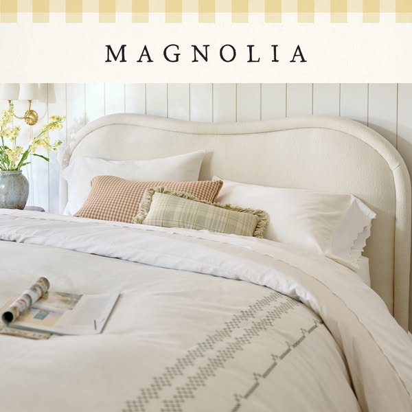 This ad showcases a white bedding set from Magnolia. The product is displayed on a neatly made bed with several pillows 
