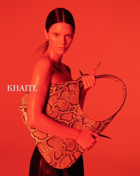 This ad features a portrait shot of a woman holding a snakeskin purse. The text simply states the brand name.