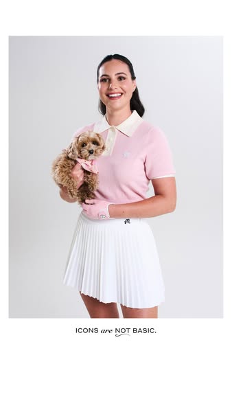 An image ad for golf apparel featuring a woman holding a small dog. The ad is focused on a collared shirt and skirt, and