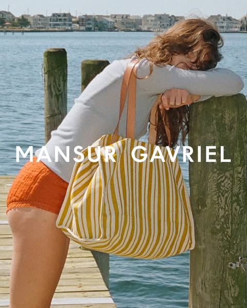 This ad features a woman leaning against a wooden pier near the water, with a striped tote bag hanging on her shoulder. 