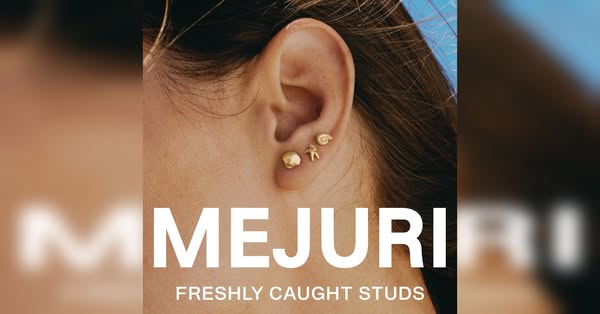 This image ad for Mejuri features a close-up of a woman's ear adorned with three Mejuri stud earrings. The focus is 