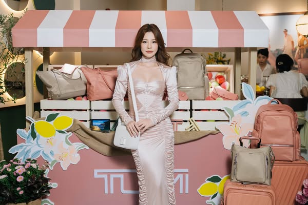 This image ad features an Asian female model showcasing a range of TUMI travel products in a stylized setting reminiscen