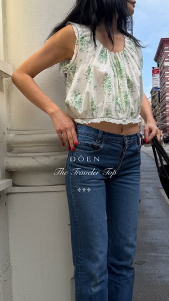 This ad showcases the DÔEN "The Traveler Top" in a real-world context by featuring it on a model in an urban s