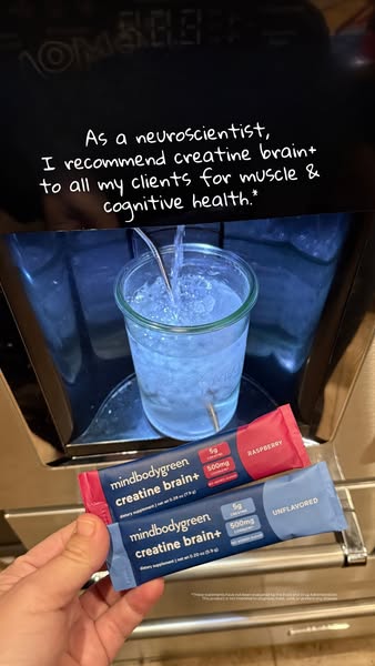 This image ad features two creatine brain+ supplement packets from mindbodygreen, with a glass of water being filled in 
