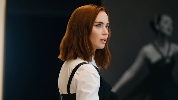This ad features a close-up of a woman looking to the side. She is wearing a white blouse and black overalls, and she ha