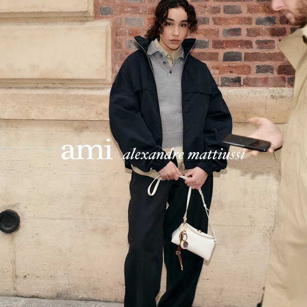 This ad features a woman dressed in Ami clothing, holding a purse, and standing in front of a brick wall. A man is shown