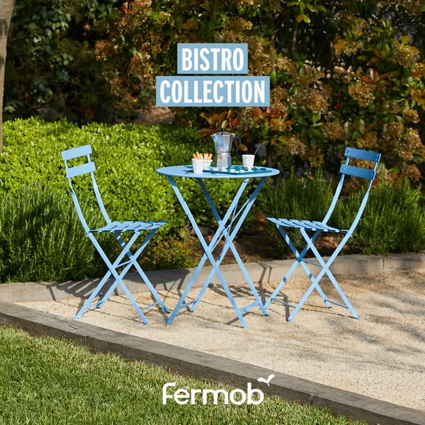 This image ad showcases a light blue Fermob Bistro Collection table and two chairs in a garden setting. The ad aims to e