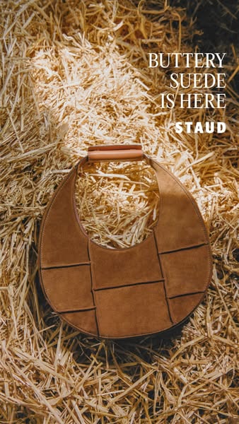 This ad showcases a brown suede handbag from STAUD. The bag is displayed against a backdrop of hay, emphasizing its text