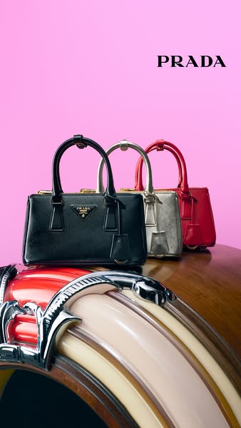 This ad showcases three Prada Galleria mini bags in different colors, arranged on top of a vintage-style jukebox. The br
