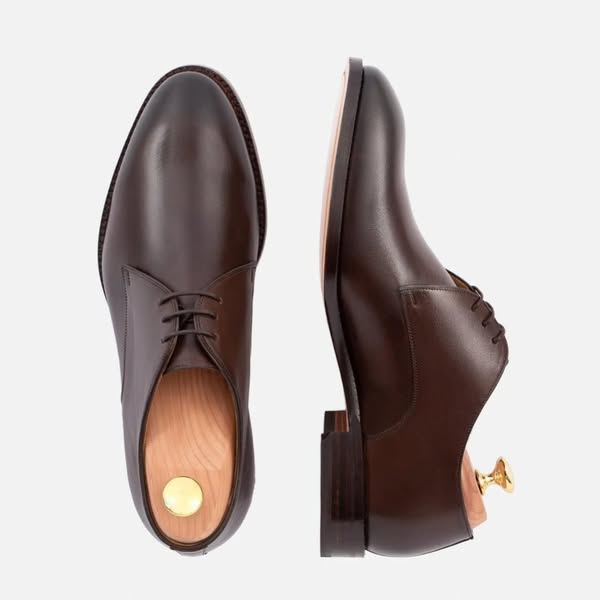 This ad showcases a pair of brown leather dress shoes, emphasizing their quality and craftsmanship.