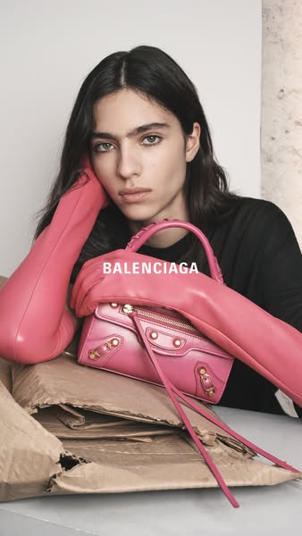 This image showcases a pink Balenciaga handbag being held by a model wearing pink gloves.