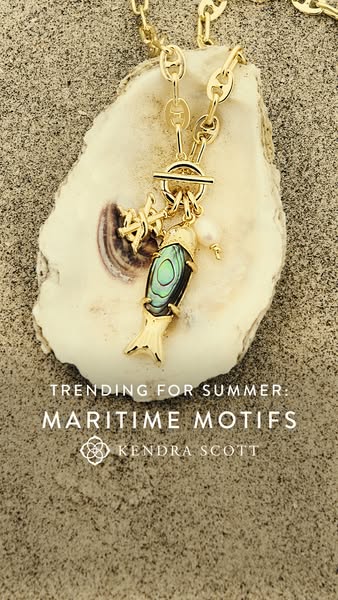 The ad features a close-up shot of a gold necklace with a fish pendant on an oyster shell on a sandy surface. The ad pro