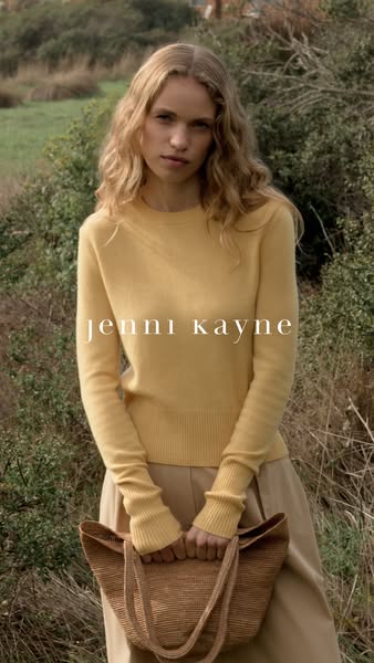 This is a product photo ad featuring a woman holding a tote bag and wearing a sweater from Jenni Kayne.