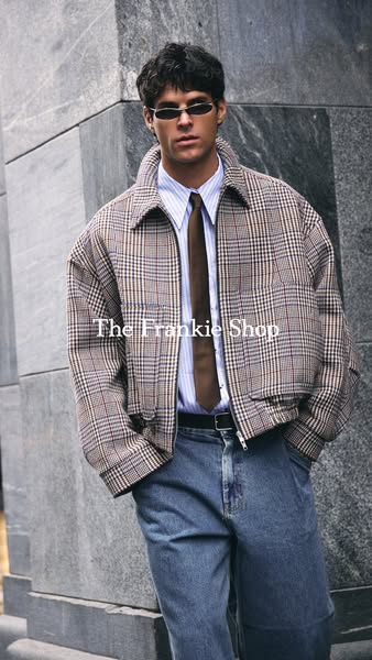 This image ad features a man wearing a jacket from The Frankie Shop. The man is standing outside against a building and 