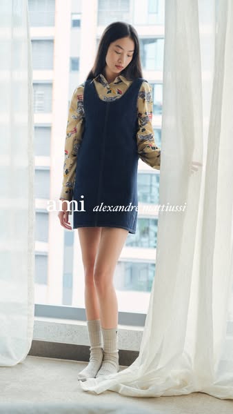 This ad features a woman wearing a denim dress from the brand ami alexandre mattiussi. The ad is a full shot of the woma