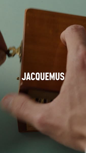 The ad features a hand opening a wooden box with the brand name JACQUEMUS in the center.