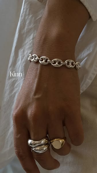 The ad features a person's hand adorned with a silver bracelet and rings, showcasing the jewelry brand Kinn.