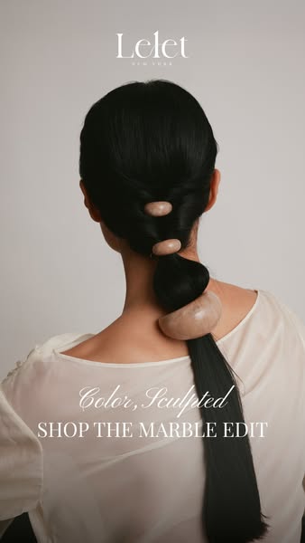 This image ad for Lelet NY features a woman with long black hair styled in a ponytail with three marble hair accessories