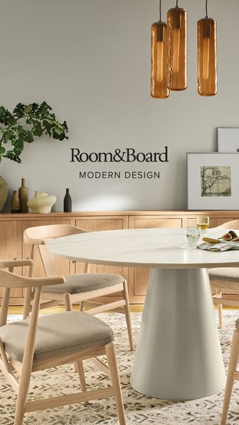 This image showcases a modern dining room setup by Room & Board, featuring a round table and chairs, emphasizing con
