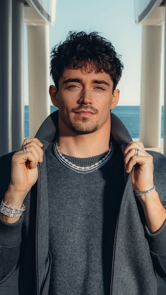 An ad featuring Charles Leclerc showcasing jewelry. He is wearing several pieces, including necklaces, bracelets, and ri