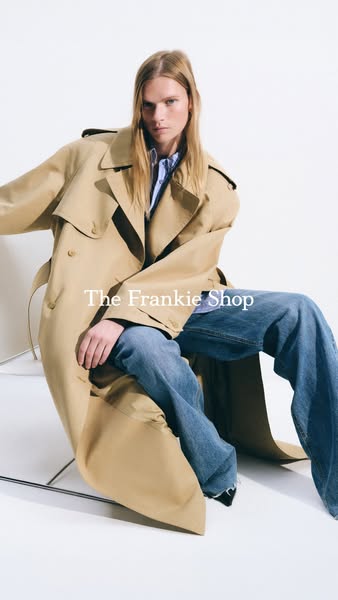 This image ad for The Frankie Shop features a person sitting on a stool and wearing a tan trench coat with jeans.