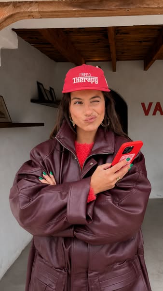 This image ad features a woman wearing a hat that reads "I NEED Therapy." She is wearing a large jacket and ho