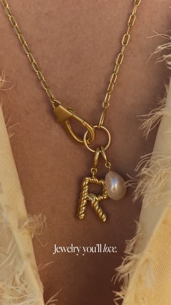 This ad features a close up view of a gold chain with an R pendant and pearl. The text below reads "Jewelry you'