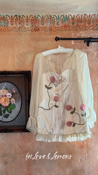 This image ad for For Love & Lemons features a cream colored top on a hanger. The overall visual style is vintage-in