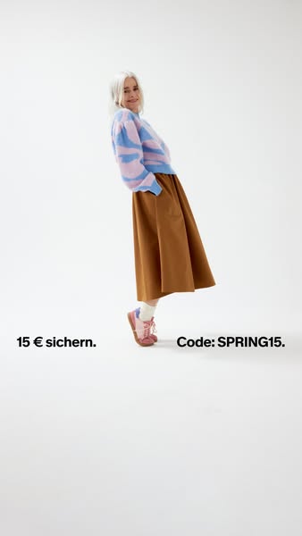 This is a static image ad for a fashion retailer. It features a model wearing a sweater, skirt, and shoes that are avail