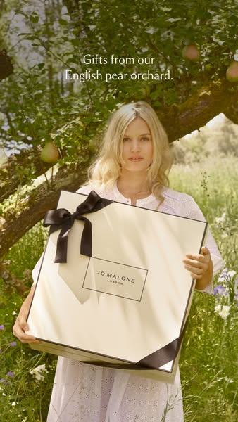 This ad features a woman in a pear orchard holding a large gift box from Jo Malone London. The ad is meant to promote th