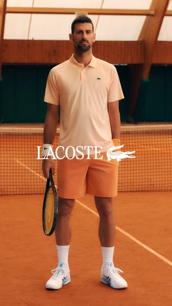 This Lacoste ad features tennis player Novak Djokovic wearing a light orange polo shirt and shorts while standing on a t