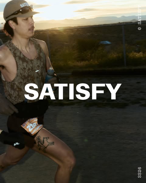 This image ad shows a runner, presumably wearing Satisfy brand activewear, running on a dirt road through the desert.