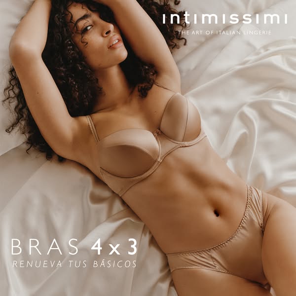This image ad for Intimissimi features a woman wearing a beige bra and underwear set on a satin sheet. The ad highlights