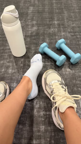 An image ad showcasing a pair of bombas socks being worn with athletic shoes, alongside a water bottle and dumbbells. Th