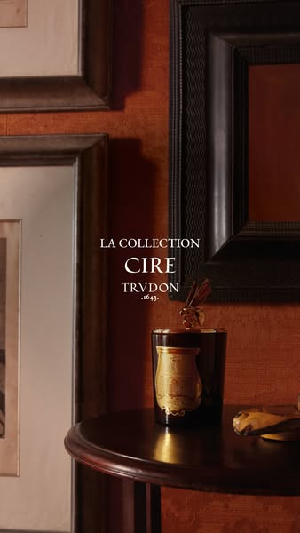 A close-up of the 'Cire' candle from Trudon set in a traditionally decorated room with paintings on the wall.