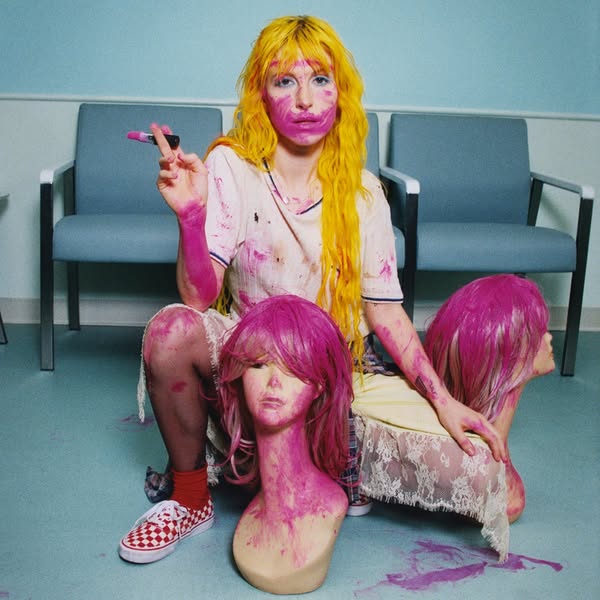 This ad features an image of a person with bright yellow hair and lipstick smeared on their face, holding a lipstick tub