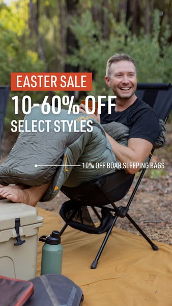 A man smiles in a sleeping bag while sitting in a chair outside. The ad is an announcement for an Easter sale.