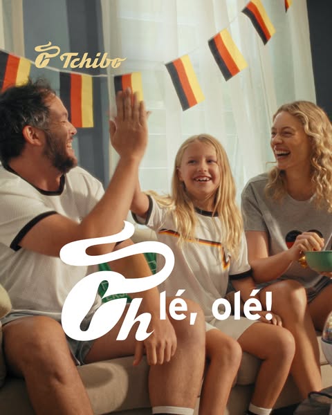 A family is sitting on a couch watching soccer. They are celebrating.