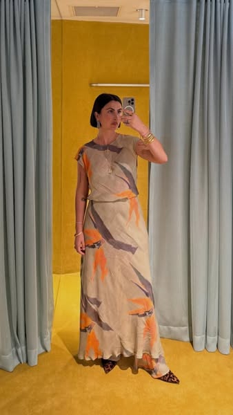 An image ad shows a woman posing in a mirror, wearing a printed maxi dress. She holds up her cell phone to take a photo