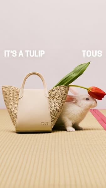 Image ad showcasing the TOUS brand, featuring a woven bag alongside a white rabbit and a tulip, with the playful text