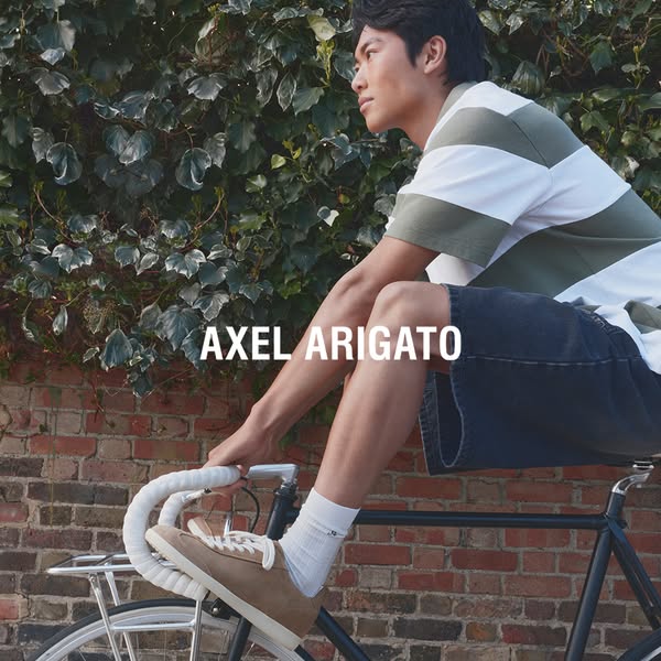 The ad features a stylish man on a bicycle wearing Axel Arigato shoes. The overall aesthetic emphasizes a relaxed and ef
