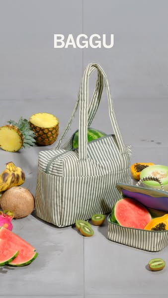 A still image featuring a BAGGU bag filled with fresh fruits, set against a neutral background. The composition focuses 