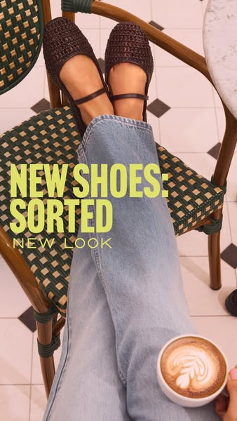 This image ad features a pair of brown woven flats being worn indoors at a cafe, styled with light-wash denim and paired