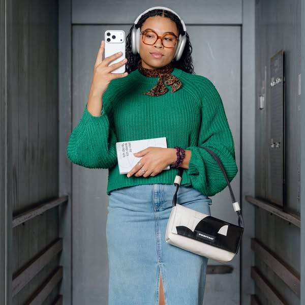 The ad features a photo of a person standing in an elevator, holding a phone and posing with the Freitag brand bag. The 