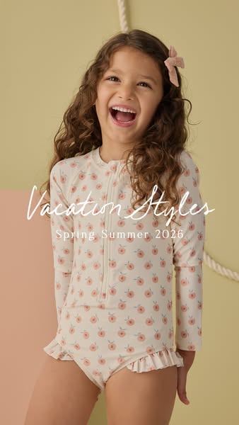 A young girl smiles while wearing a floral one-piece swimsuit.