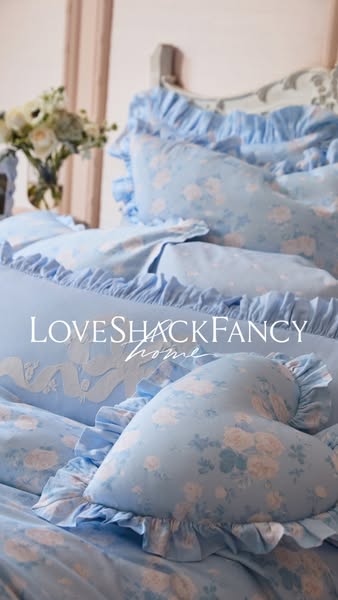 This image ad showcases LoveShackFancy Home products, specifically their bedding collection, which features a soft, ligh