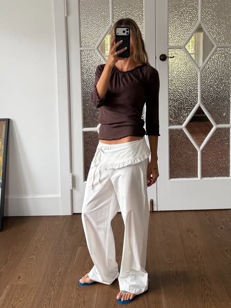 The ad features a woman standing in front of a door, wearing a brown top and white pants. She is holding a phone up, pre